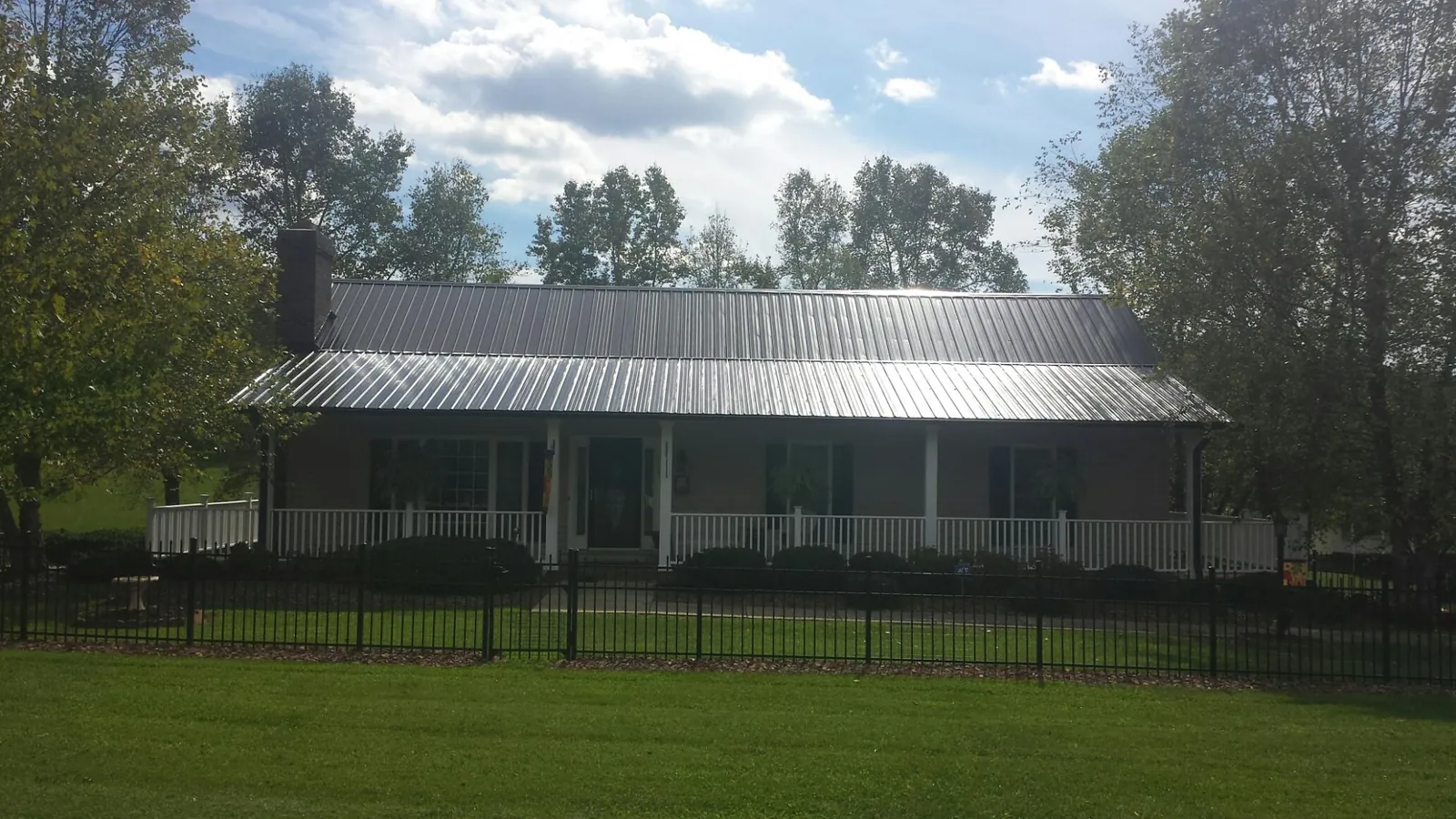 Gray metal roof on a brick ranch with a full width front porch — Gutter Guard Installation work by our crew in Pleasantville